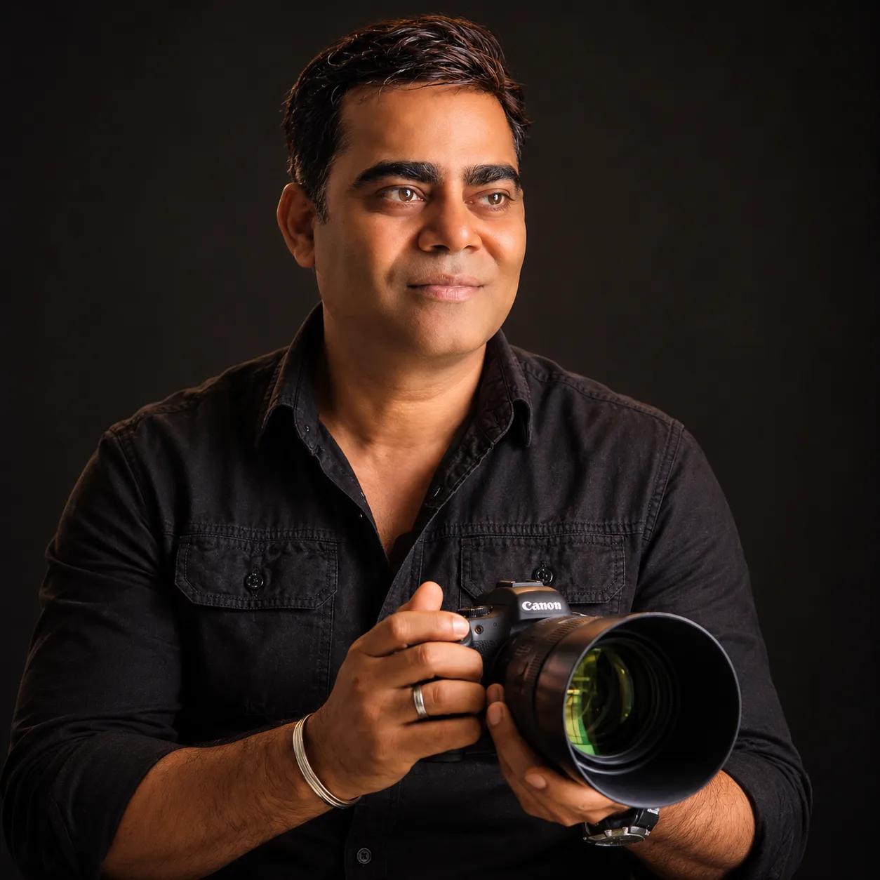 Vivek Pankaj, Bangalore photographer, in a black shirt holding a Canon camera against a dark studio backdrop