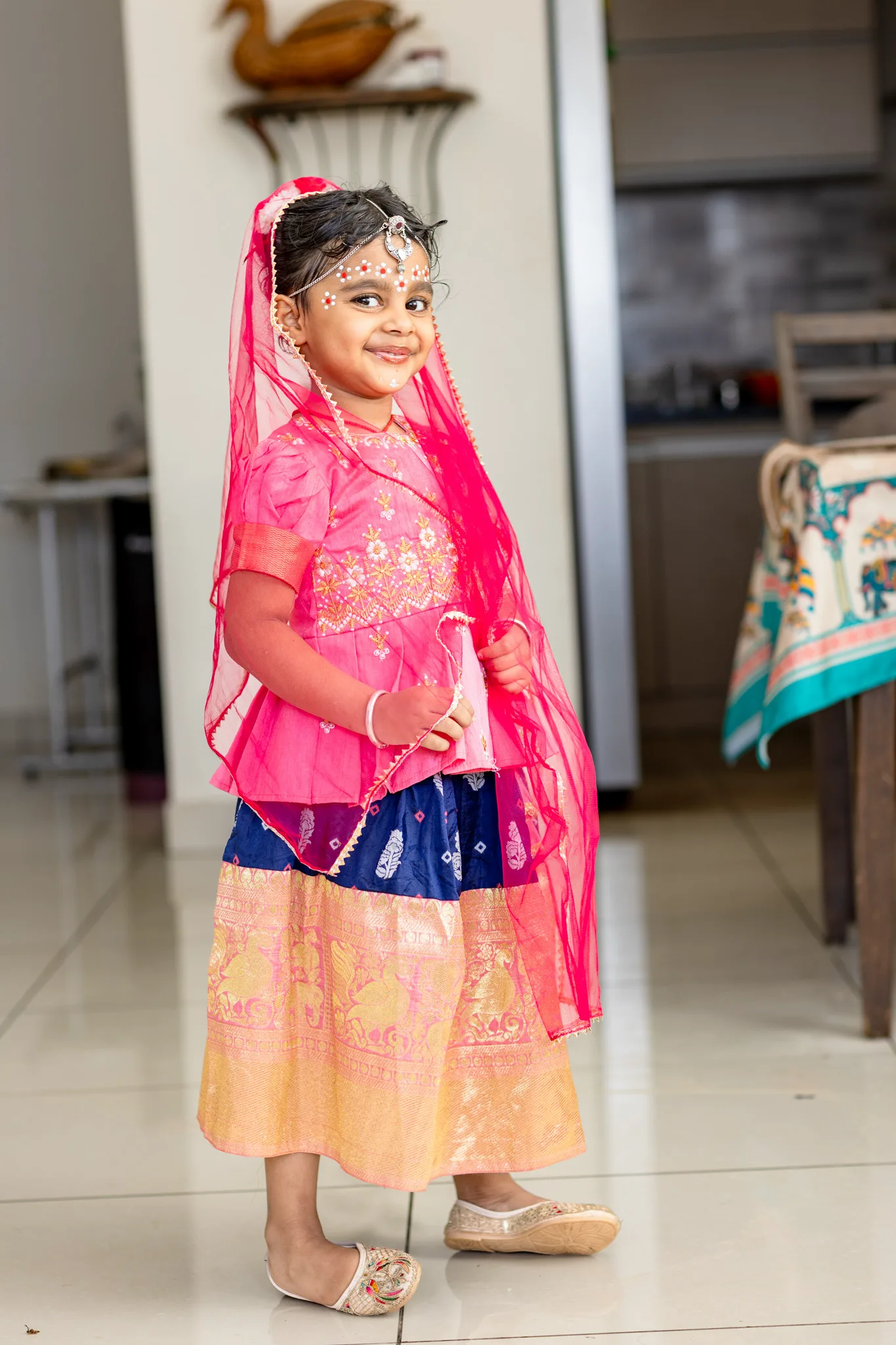 Smiling little girl in a pink and gold lehenga with a matching dupatta at home, festive kids portrait by Vivek Pankaj