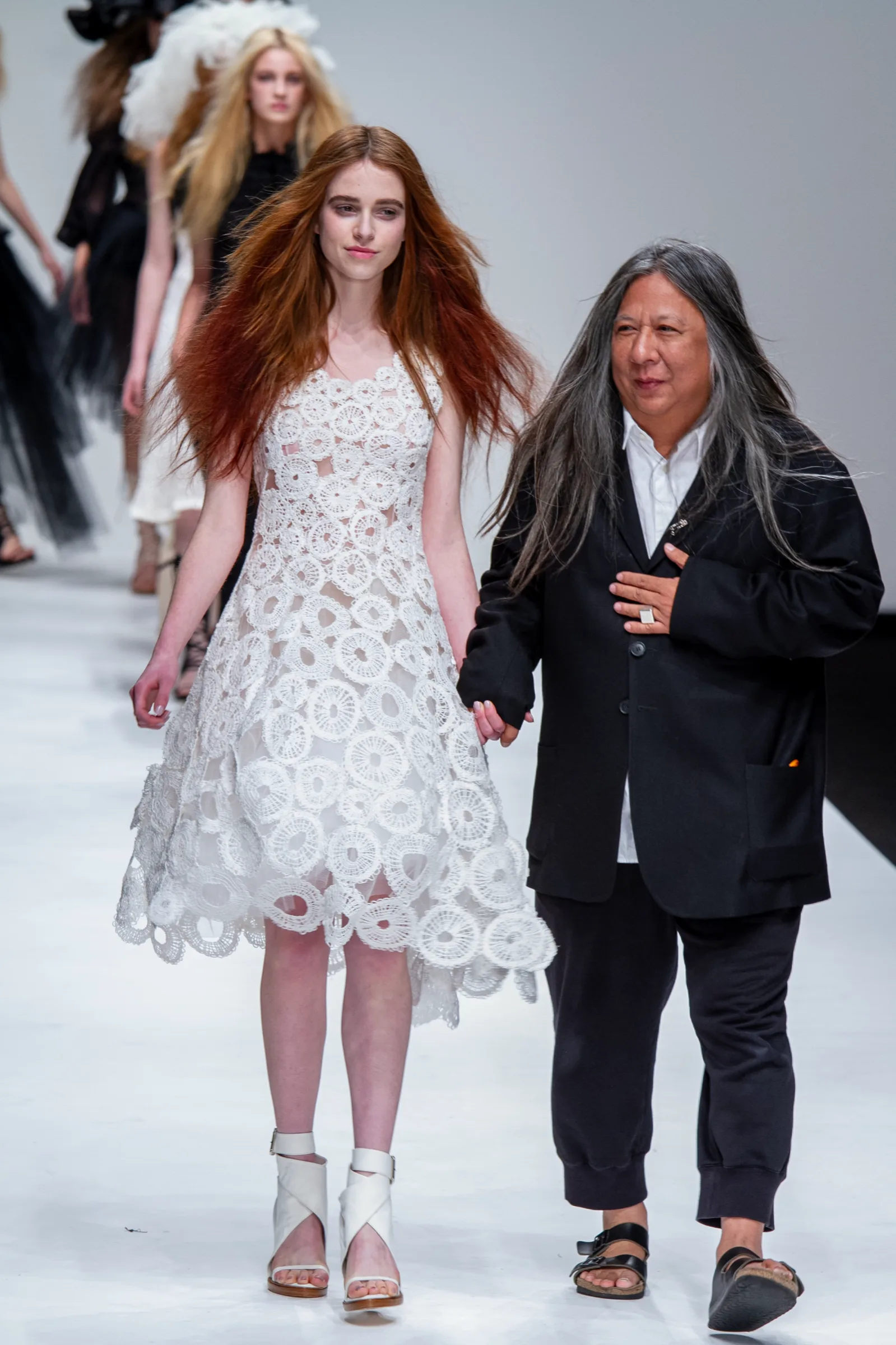 Designer walks the runway finale hand in hand with a model in a white crochet-lace dress at London Fashion Week, photographed by Vivek Pankaj