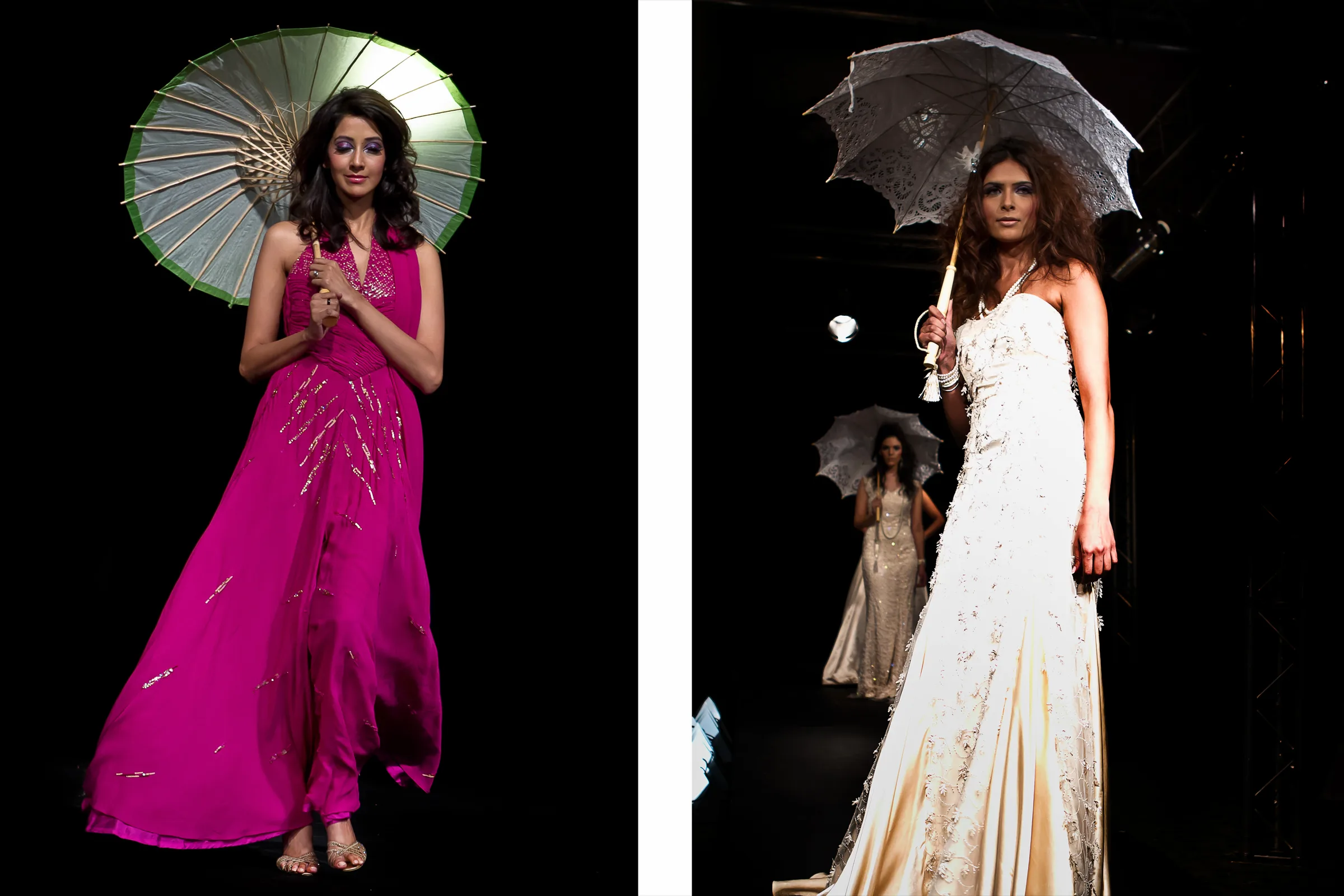 Model in a magenta gown with a paper parasol and a model in an ivory gown with a lace umbrella on a dark runway, photographed by Vivek Pankaj