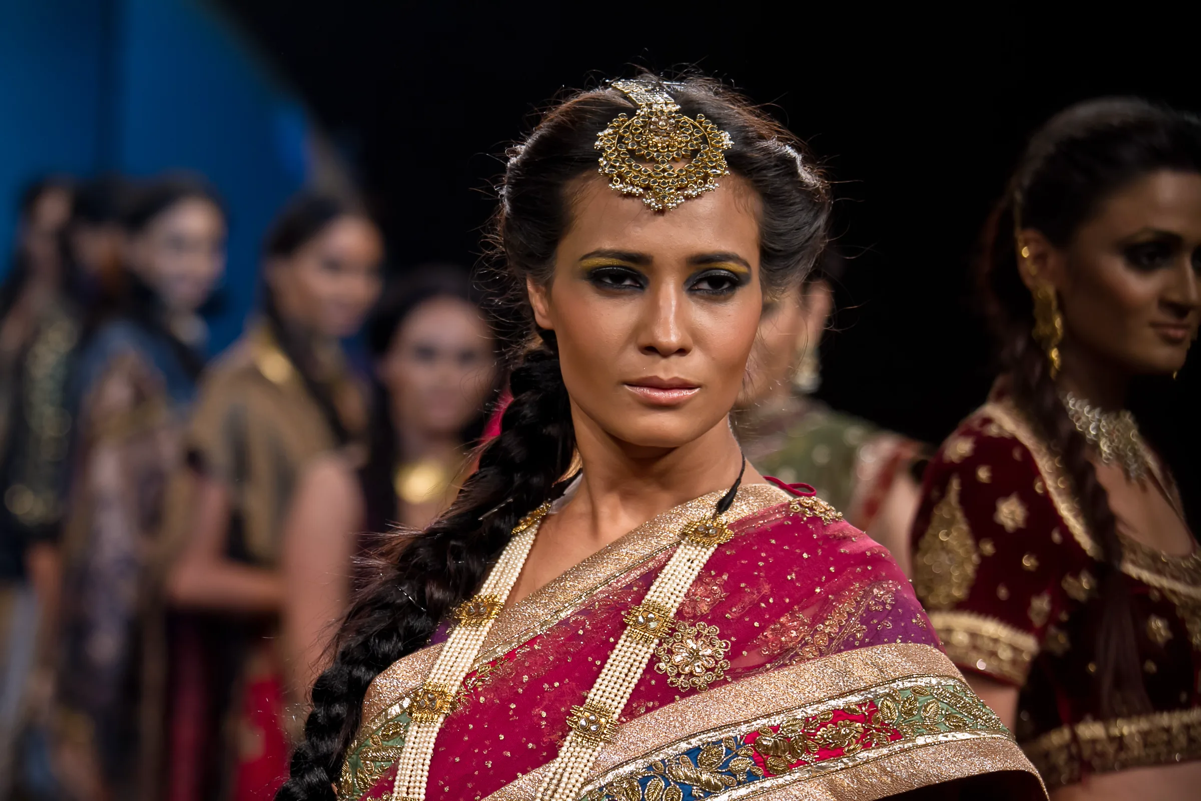 Model in a pink and gold bridal saree with a maang tikka and braid, close up on the runway at Bangalore Fashion Week, photographed by Vivek Pankaj