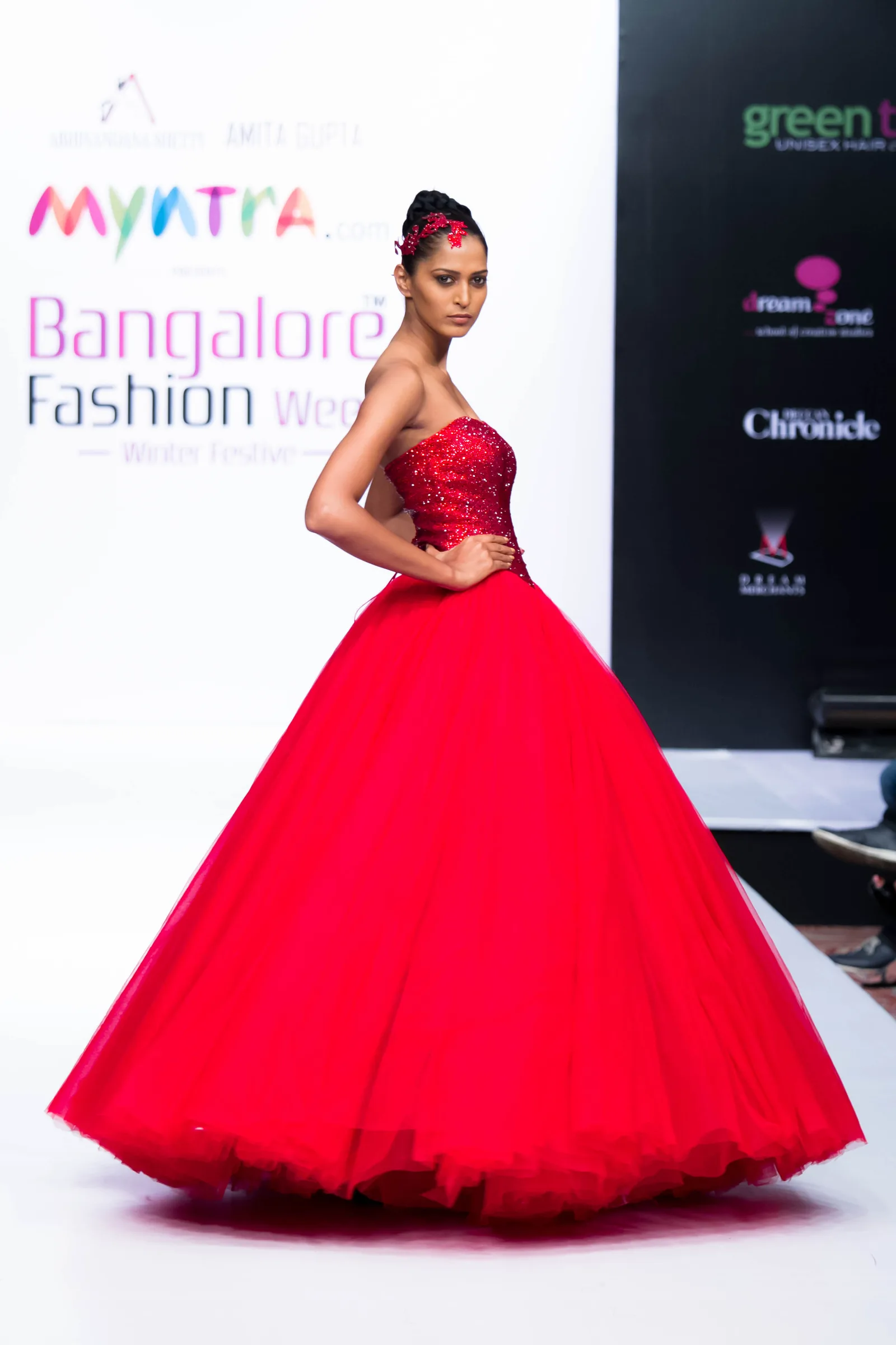 Model in a strapless red ball gown with a full tulle skirt on the runway at Bangalore Fashion Week, photographed by Vivek Pankaj
