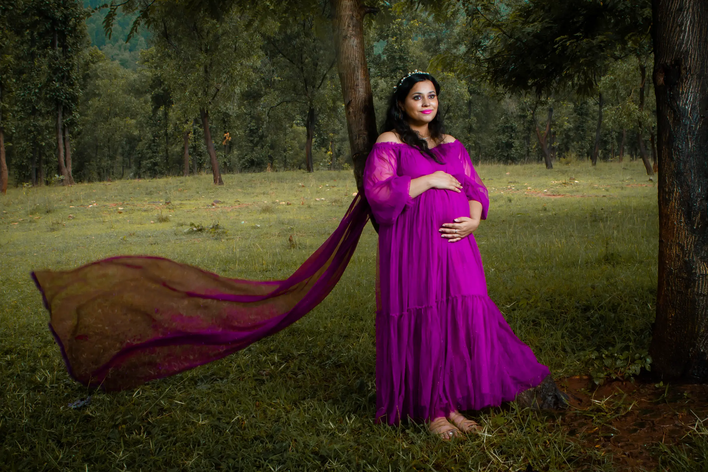 Expectant mother in a magenta gown with a long flowing trail in a wooded park, maternity photography by Vivek Pankaj